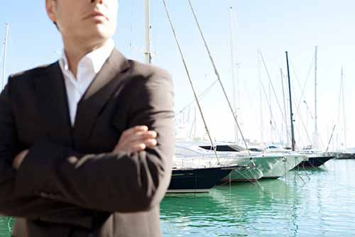 A man stands near a Yacht marina